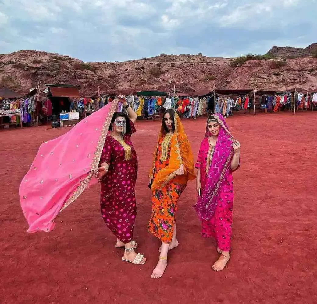 Local women in traditional dress on Hormuz Island's red earth, Iran
