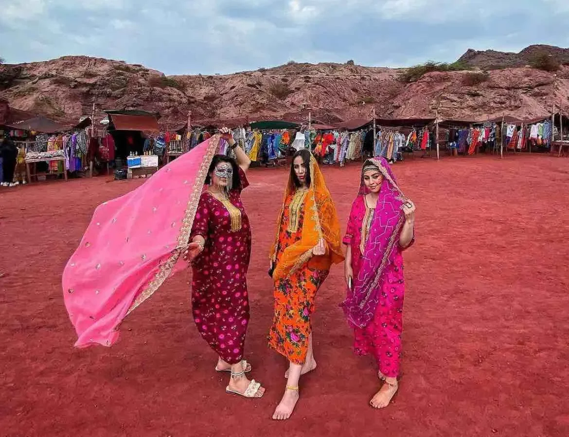 Local women in traditional dress on Hormuz Island's red earth, Iran